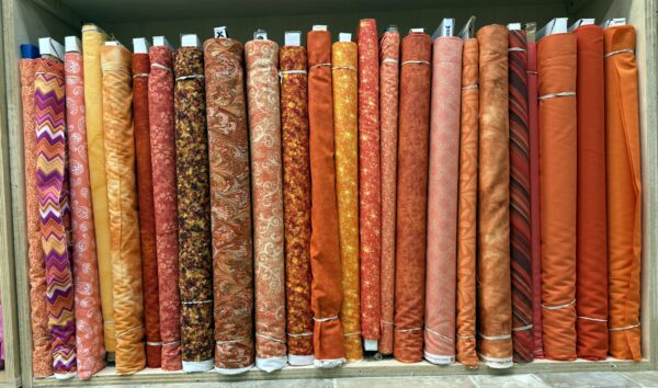 Orange tone cotton fabric bolts on the shelf