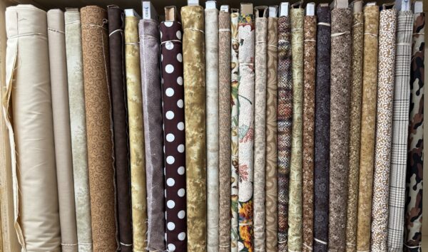 Tan and brown tone cotton fabric bolts on the shelf