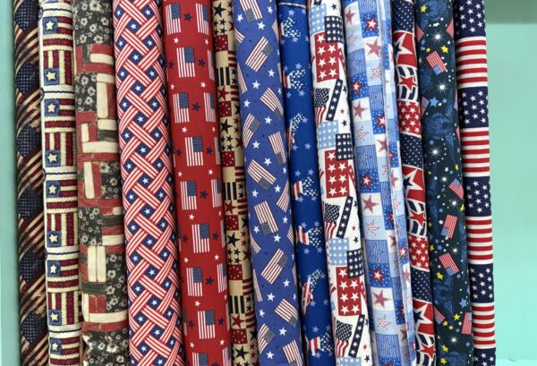 American flag and star print cotton fabric bolts on the shelf at Lady Bird Quilts